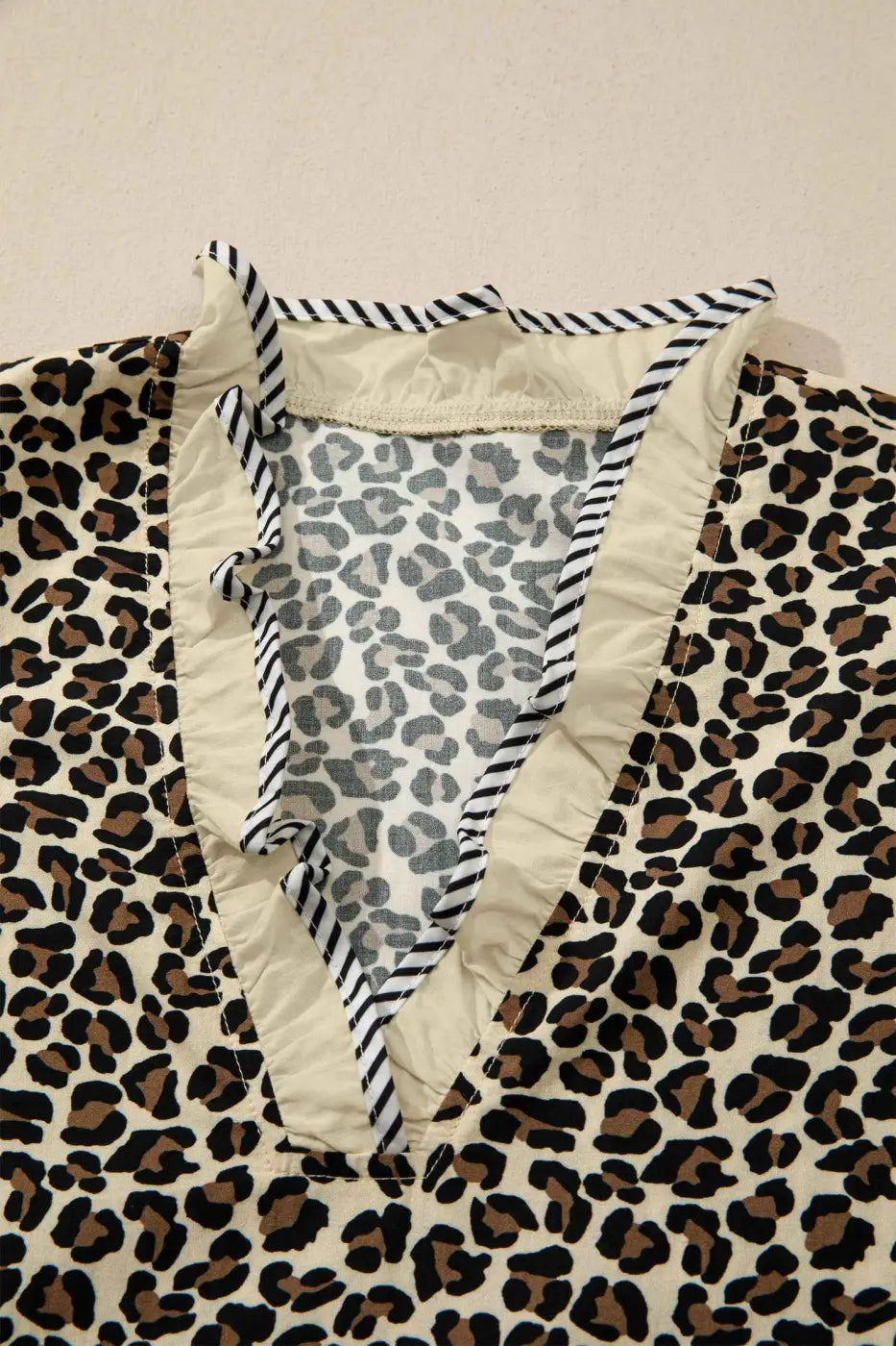 Close-up of neckline on Leopard Print Striped Trim Mini Dress showing inner stitching and striped ruffle trim for quality and design focus.