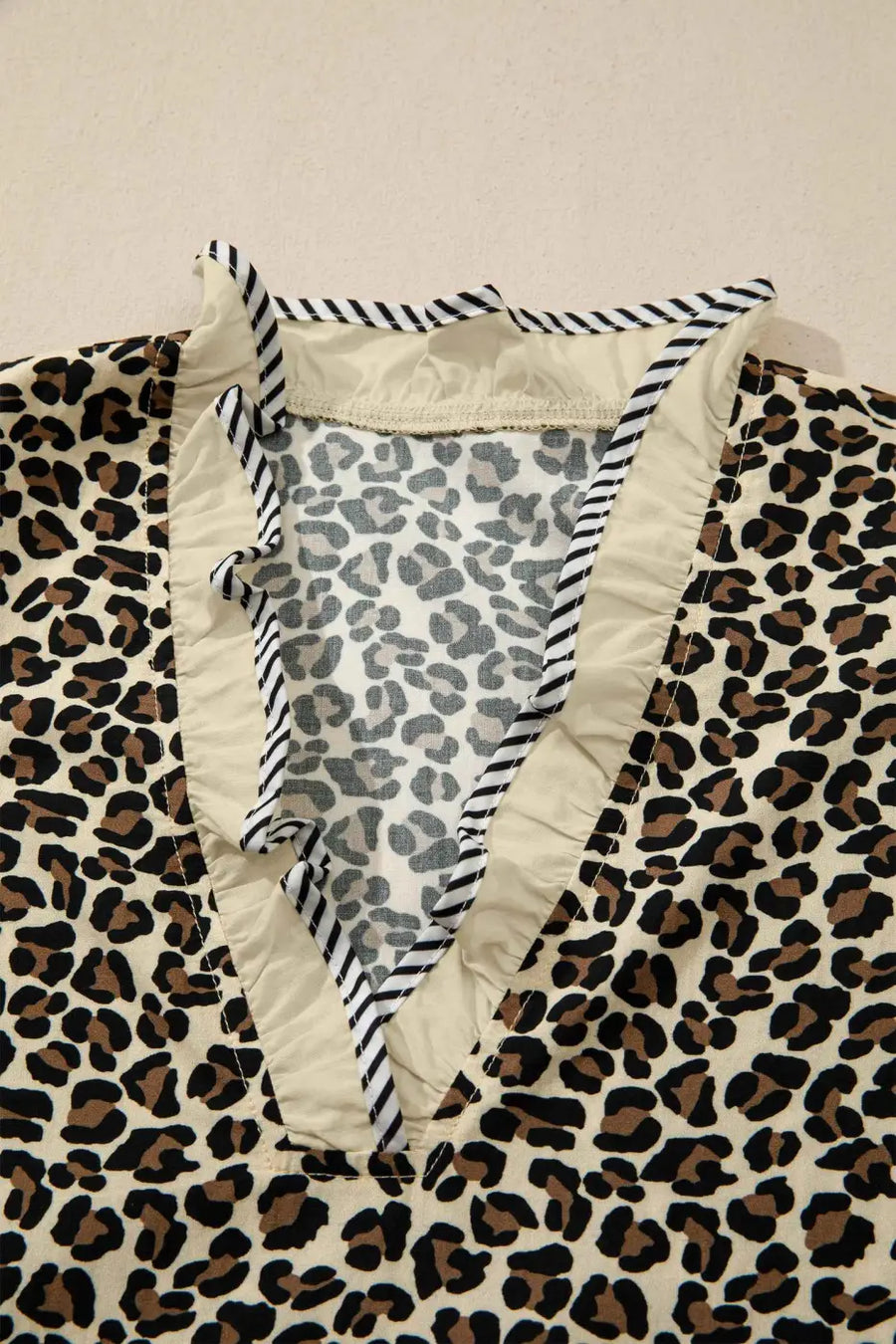 Close-up of neckline on Leopard Print Striped Trim Mini Dress showing inner stitching and striped ruffle trim for quality and design focus.
