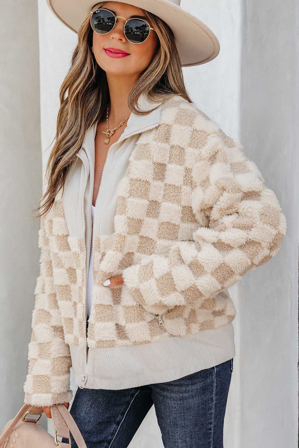 Woman wearing a Corduroy Sherpa Jacket, sunglasses, and a hat against a neutral background