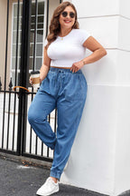 Plus Size Blue Denim Joggers styled for a casual day out, paired with a white tee and sneakers, highlighting relaxed fit and drawstring waist.