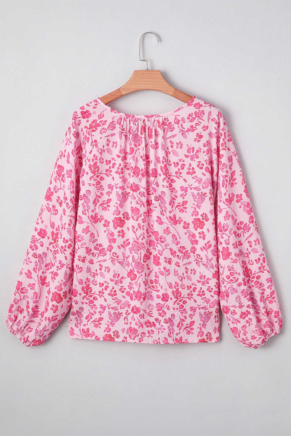 Front view of Pink Floral Lightweight Blouse on hanger, featuring v-neckline and long sleeves with floral print.
