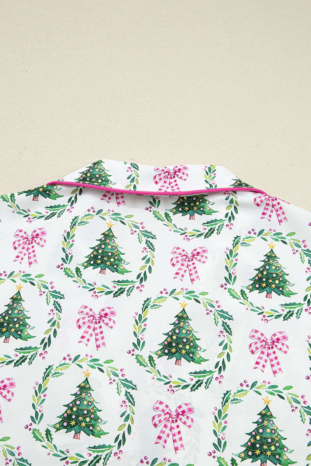 Close-up of collar on White Christmas Print Velvet Trim Pyjamas showing pink piping and holiday-themed tree and bow print.