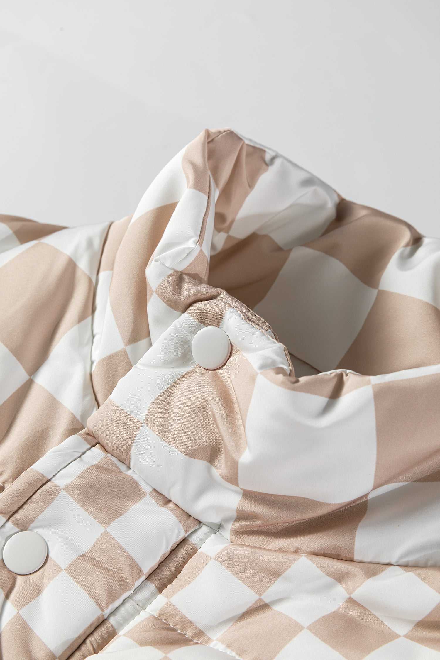 Close-up of collar and snap buttons on khaki plaid quilted gilet, showcasing high-neck design for added cold-weather protection.