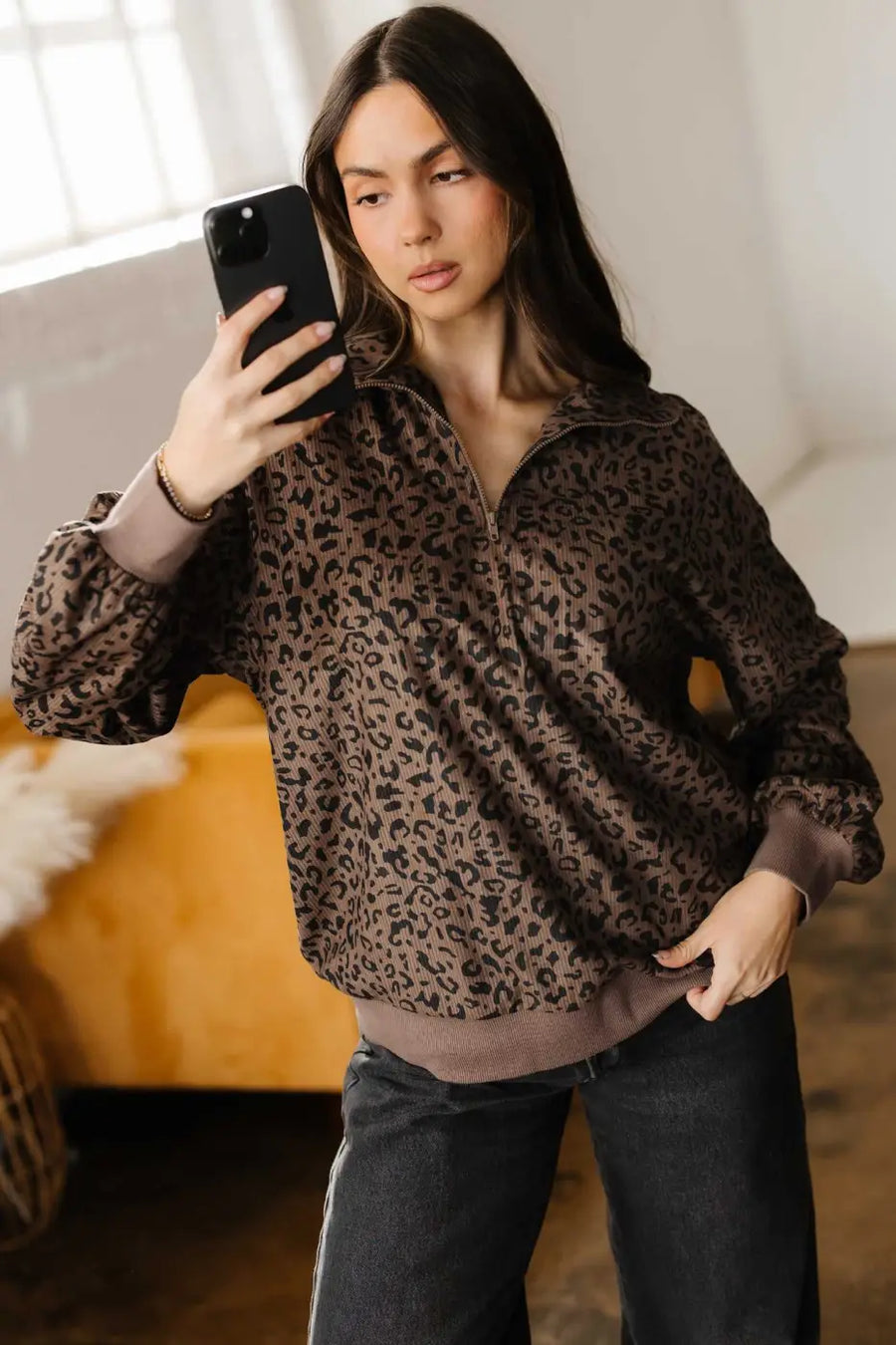 Model taking a selfie in Women's Brown Leopard Print Corduroy Half-Zip Jumper, styled with black jeans for a trendy look.