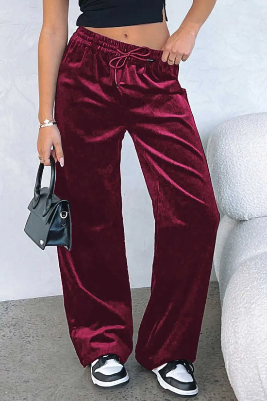 Burgundy velvet wide-leg trousers styled with a black crop top and mini handbag, ideal for casual winter outings or activewear fashion.
