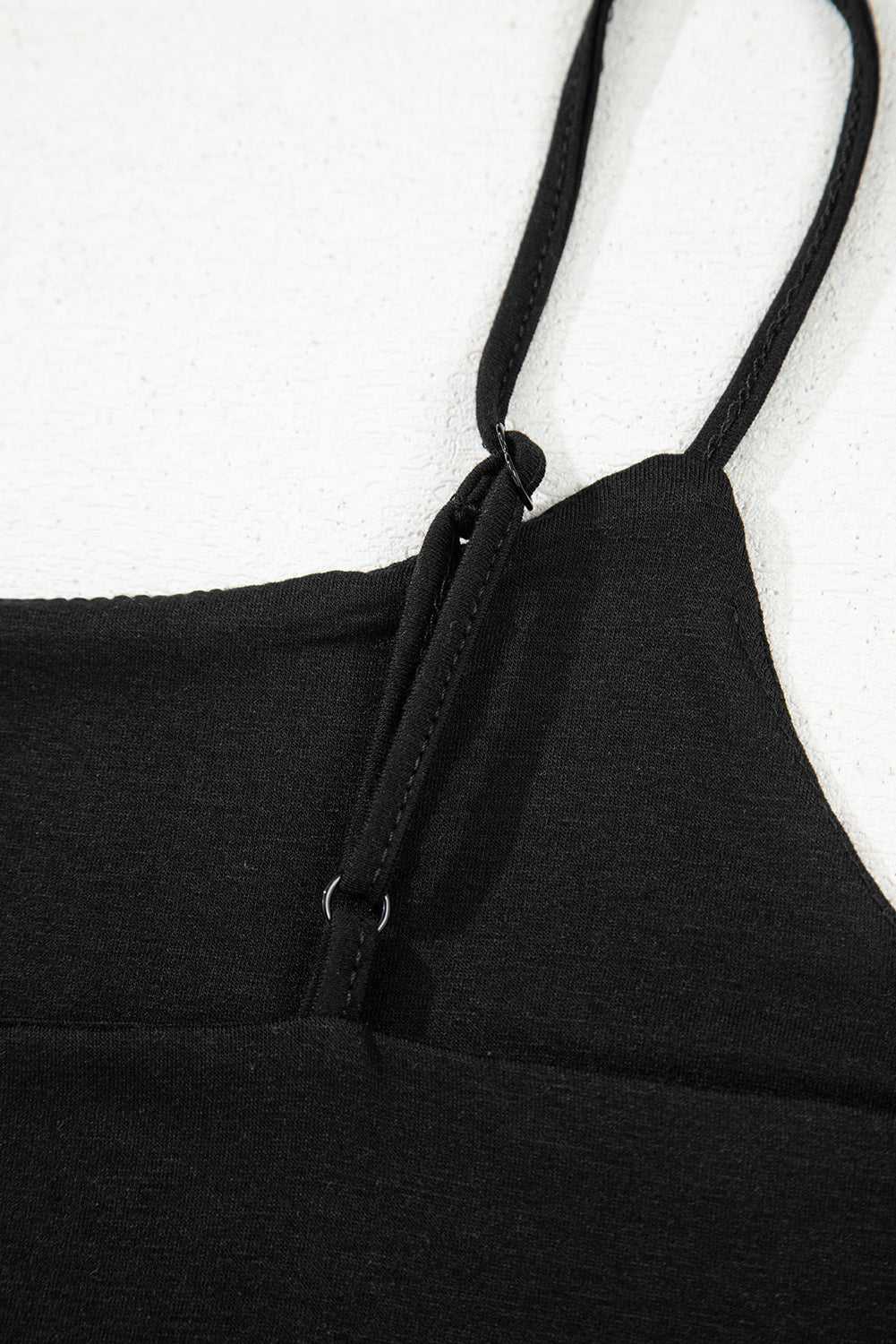 Detail of adjustable spaghetti strap on black crop top, showcasing quality stitching and stretch fabric for comfort.