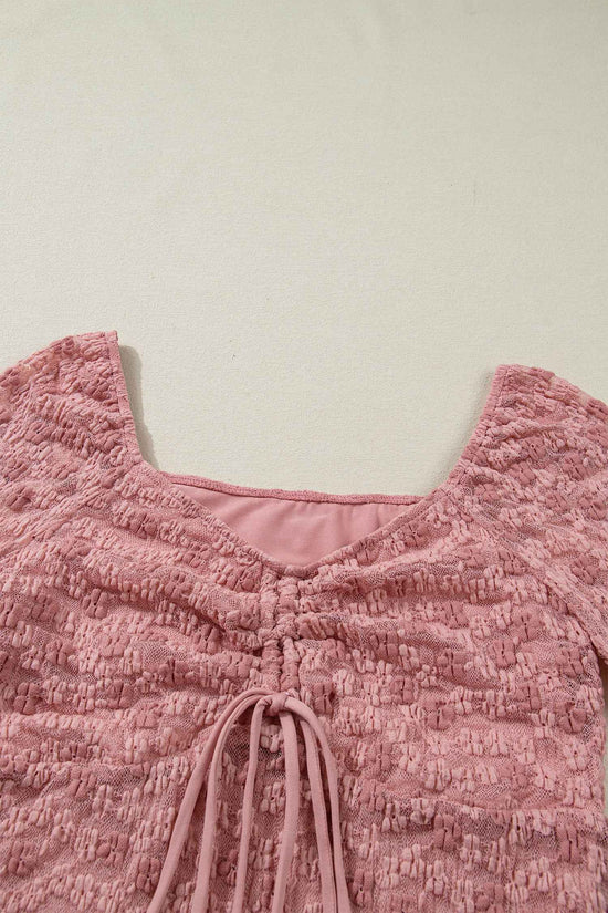 Close-up of square neckline and ruched drawstring detail on pink floral lace blouse. Soft lace texture perfect for romantic spring looks.