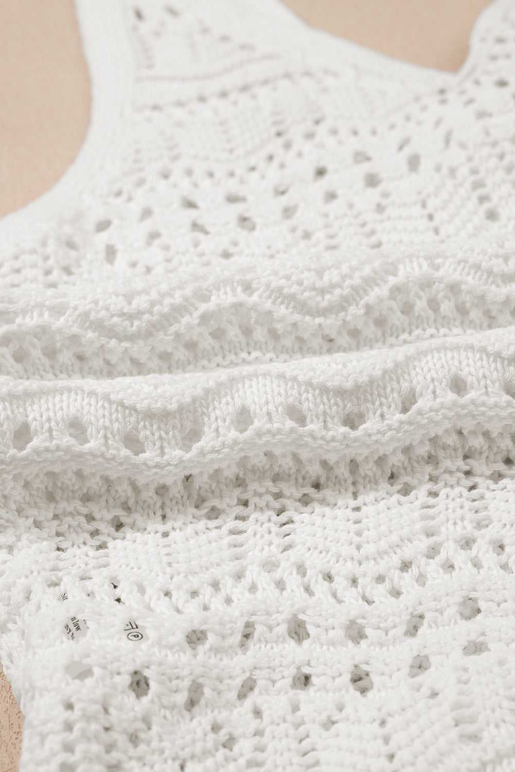 Macro shot of white crochet tank top fabric, emphasizing intricate knit pattern and soft, airy texture perfect for summer wear.