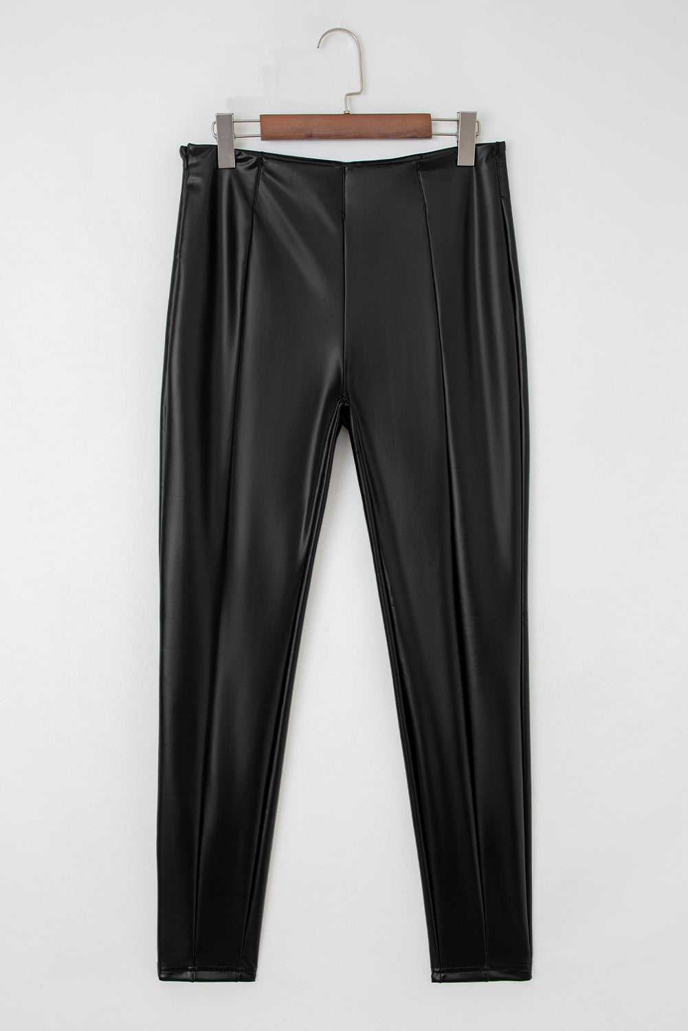 Flat lay of Black Vegan Leather Leggings – High‑Rise Skinny Fit showing front seam detailing and sleek faux leather texture.