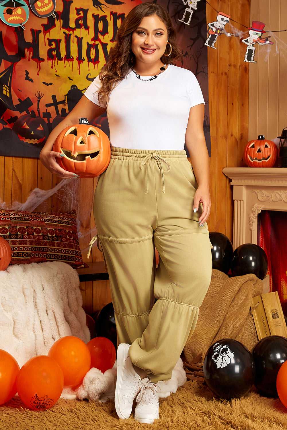 Model wearing Women's Terry Knit Drawstring Sweatpants in beige plus size, styled for a festive casual look with Halloween decor.