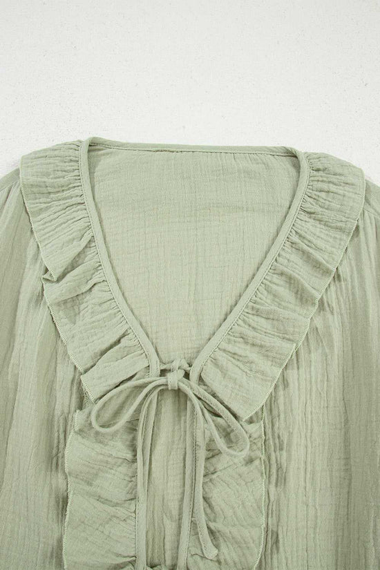 Close-up of Meadow Cotton Blouse neckline showing ruffle trim and tie detail, crafted from soft, breathable cotton fabric in solid green.