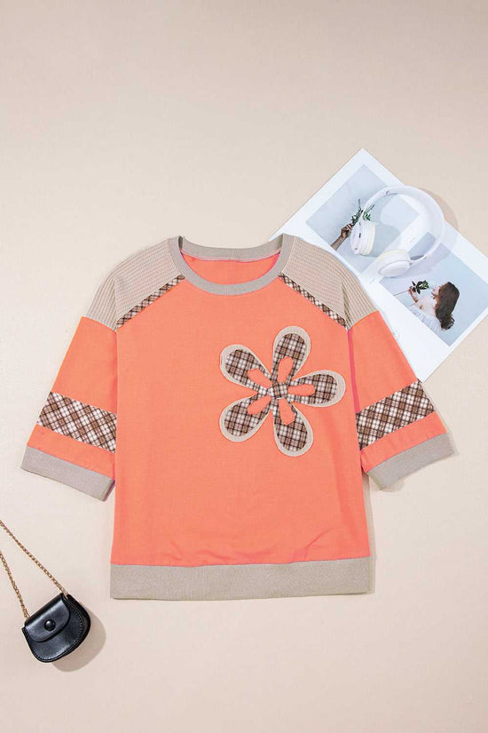 Autumn plaid floral long sleeve top in orange with patchwork flower design, waffle knit sleeves, and ribbed hem, laid flat for display.