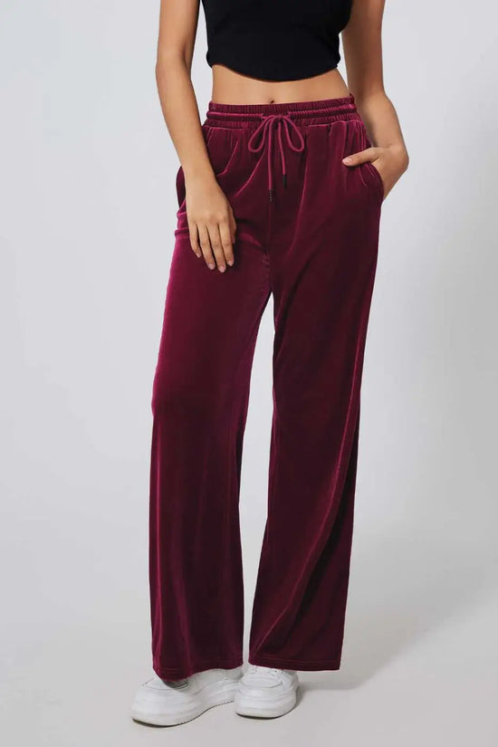 Front view of burgundy velvet drawstring trousers with side pockets and wide-leg cut, perfect for winter casual or off-duty styling.