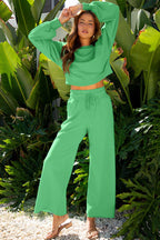 Model poses in green Drop Crop Wide-Leg Pants Set with arms raised, showcasing relaxed fit and cropped top for casual fashion.