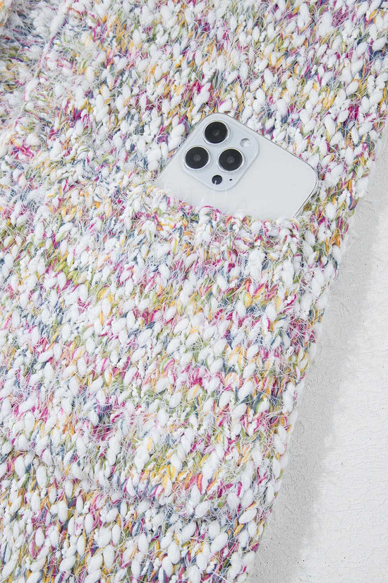 Detail of confetti knit cardigan pocket holding a smartphone, showcasing functionality and multicolor textured design.