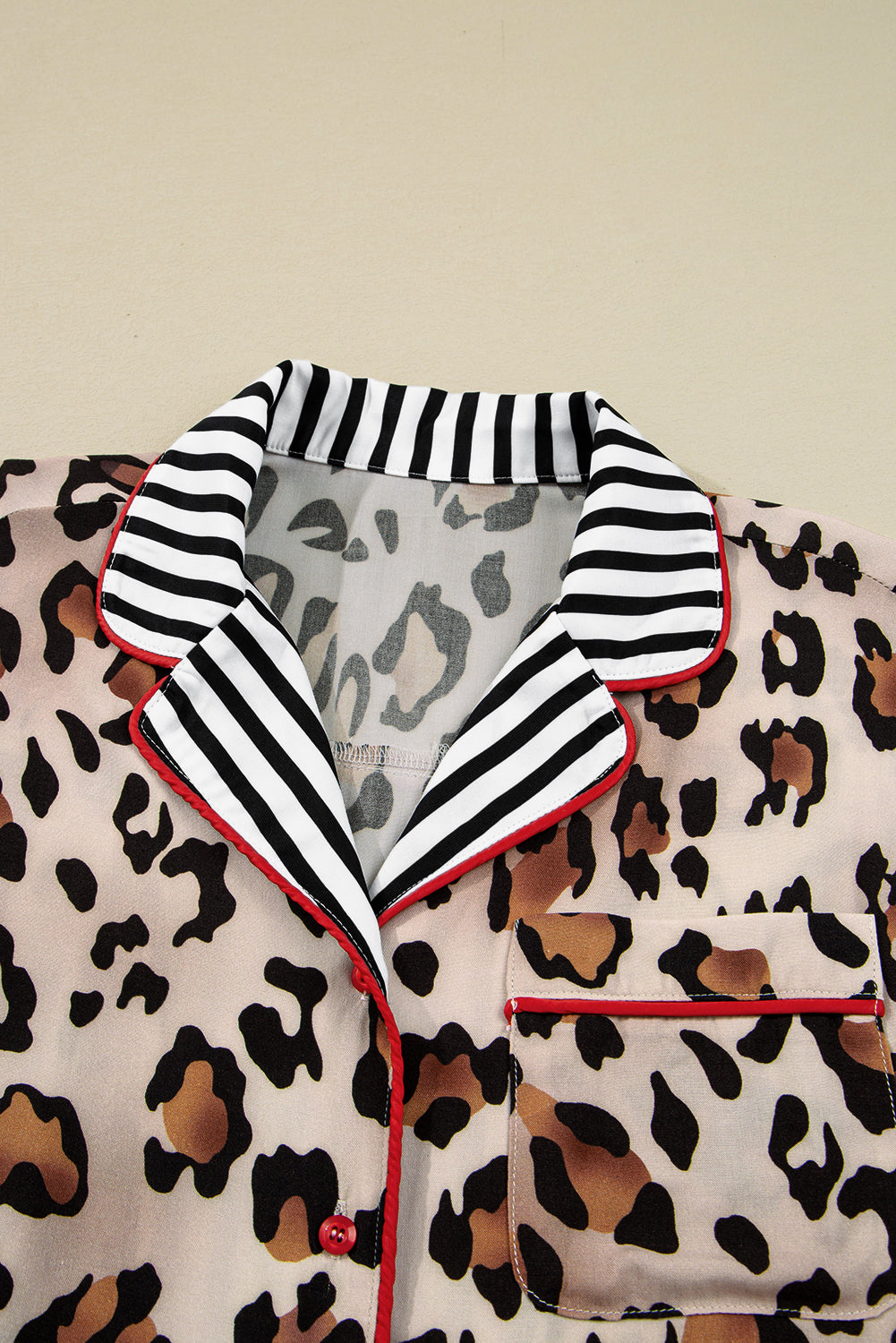 Leopard print long‑sleeve relaxed top with black and white striped collar on a beige background