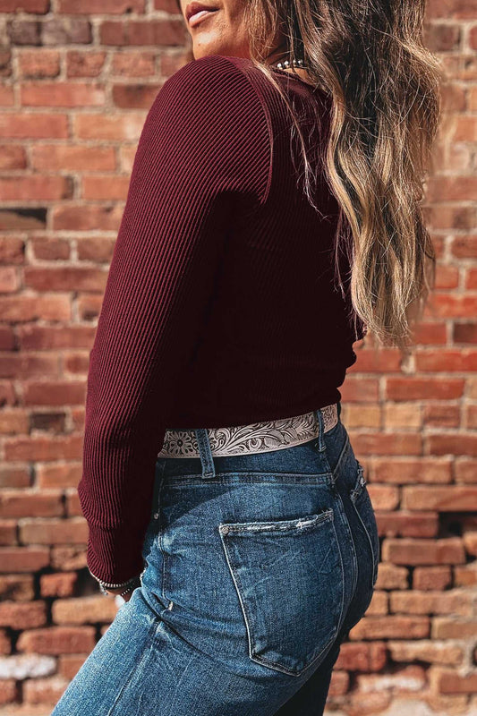 Side view of brown ribbed long sleeve crop top showing fitted silhouette and textured knit, paired with denim jeans for a casual layered look.