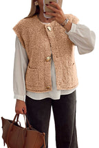Beige fuzzy fleece vest with big button accents and front pockets, layered over a white blouse and styled with a brown handbag.