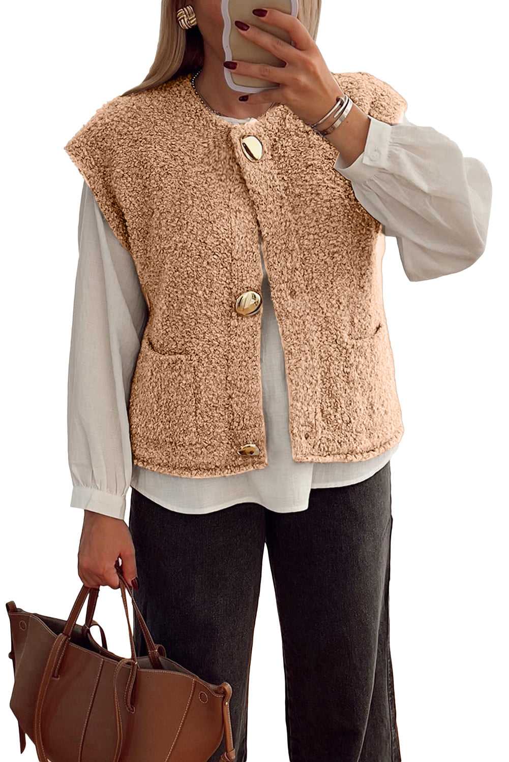 Beige fuzzy fleece vest with big button accents and front pockets, layered over a white blouse and styled with a brown handbag.