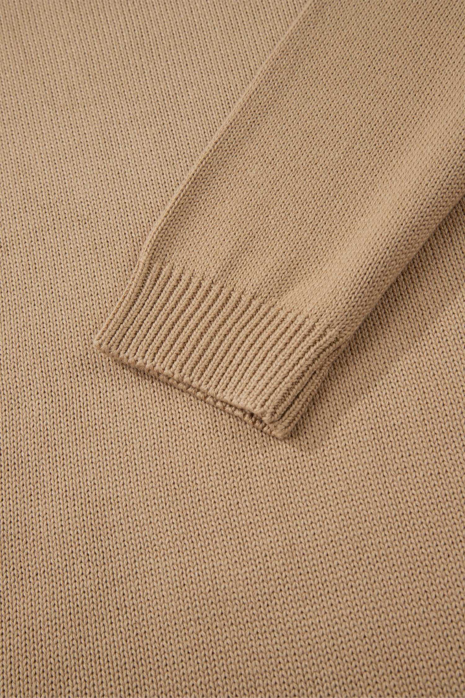 Close-up of a beige sweater with ribbed trim