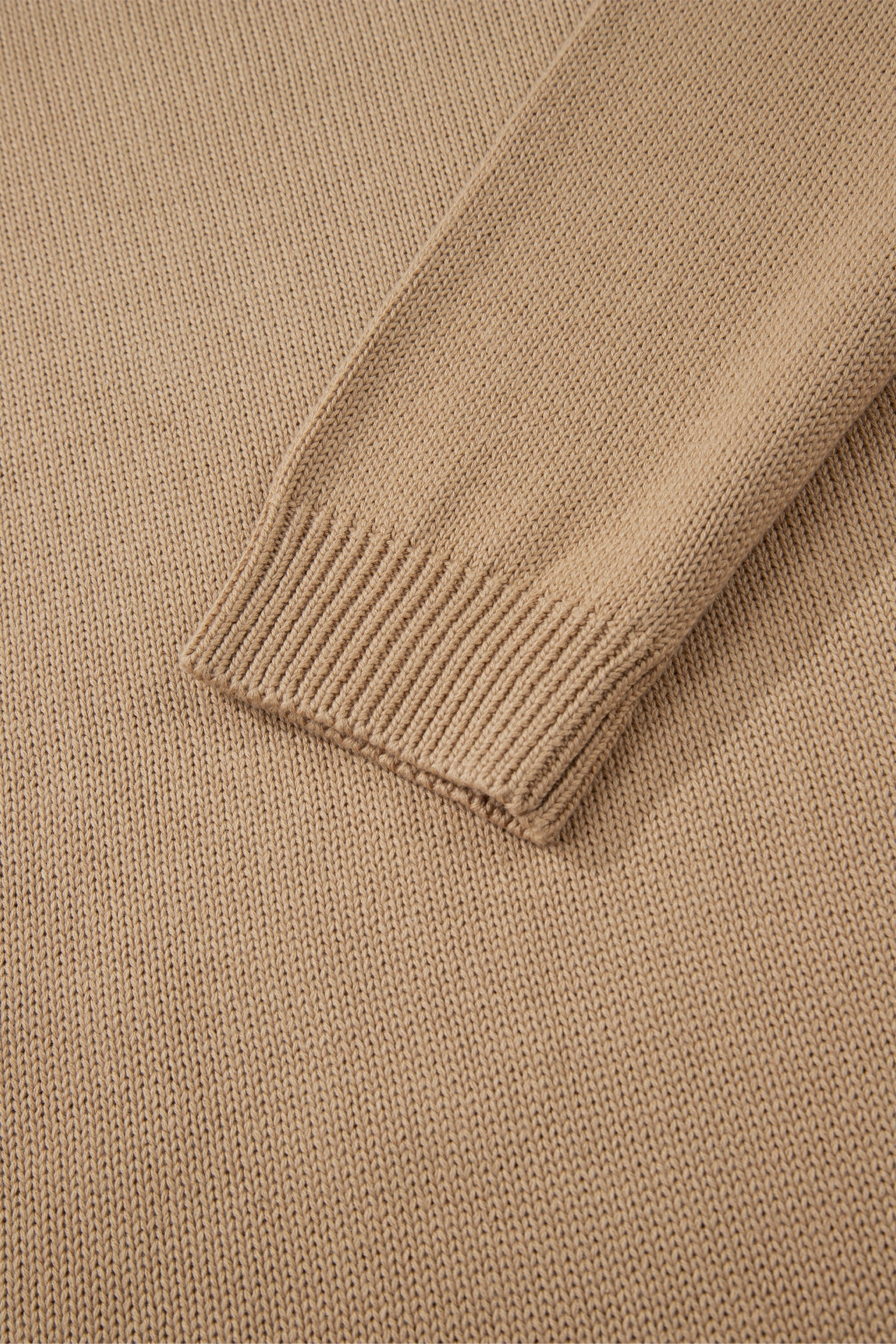 Close-up of a beige sweater with ribbed trim