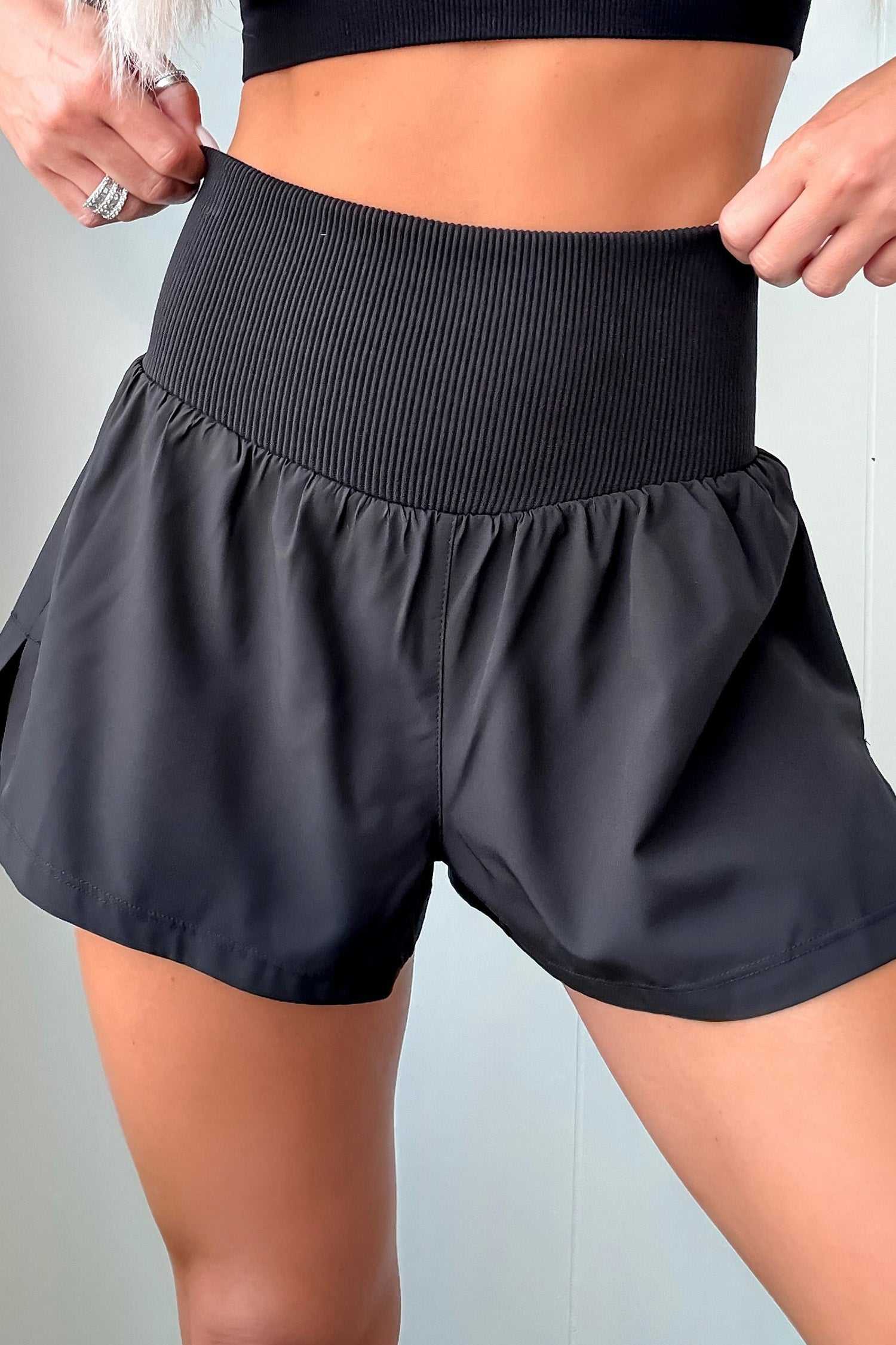 White ribbed high waist athletic shorts for women featuring a wide ribbed waistband and flowy patchwork design. Ideal for workouts and summer wear.