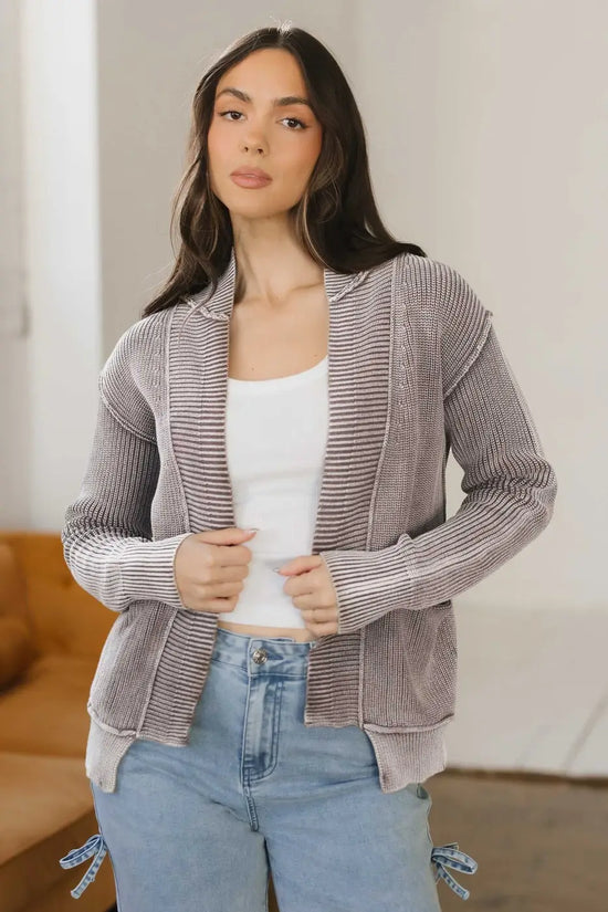 Model wearing brown Women's Stonewash Patchwork Knit Open Cardigan over white tank top and jeans, styled for casual wear.