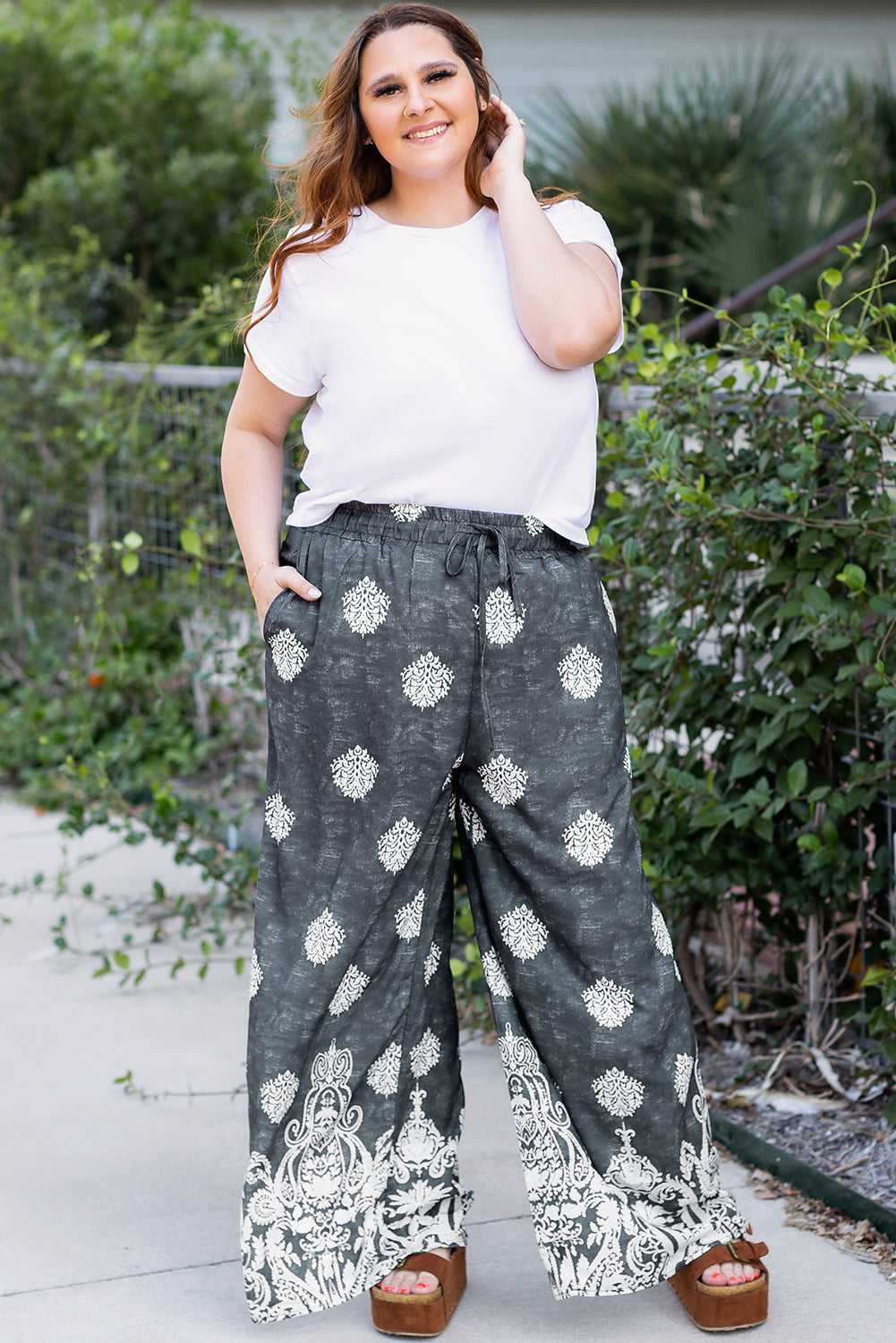 Model wearing plus size black geometric print wide leg trousers with white t-shirt, ideal for spring and summer casual outfits.