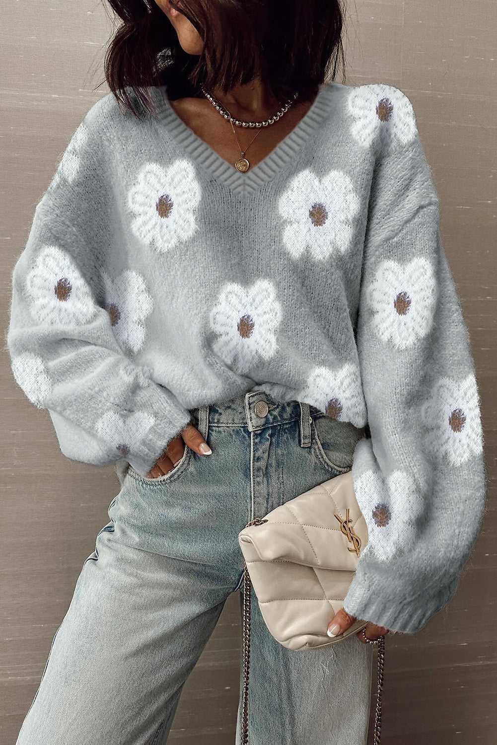 FashionFitz Oversized Grey Floral Knit Jumper – V‑Neck styled with jeans and a beige clutch, featuring soft white floral print and relaxed fit.