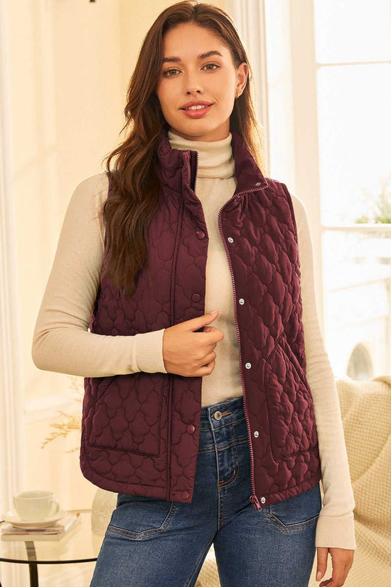 Burgundy Flower‑Quilted Winter Gilet styled indoors with turtleneck and jeans, featuring zip and snap-button closure for casual winter wear.