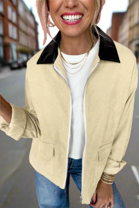Woman wearing a beige jacket with black collar against a pink background