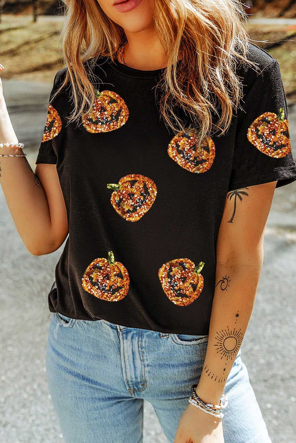Person wearing a Sequin Pumpkin Face Halloween T-Shirt and blue jeans.
