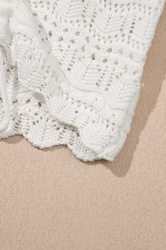 Close-up of scalloped hem on white crochet tank top, highlighting detailed summer knit fabric and lightweight texture.