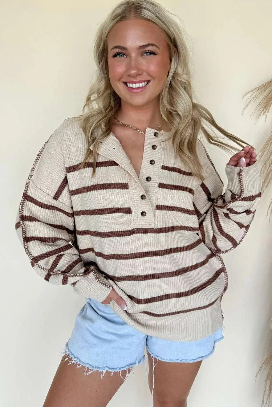 Front view of women's casual slouchy striped Henley jumper with button placket, paired with frayed denim shorts.