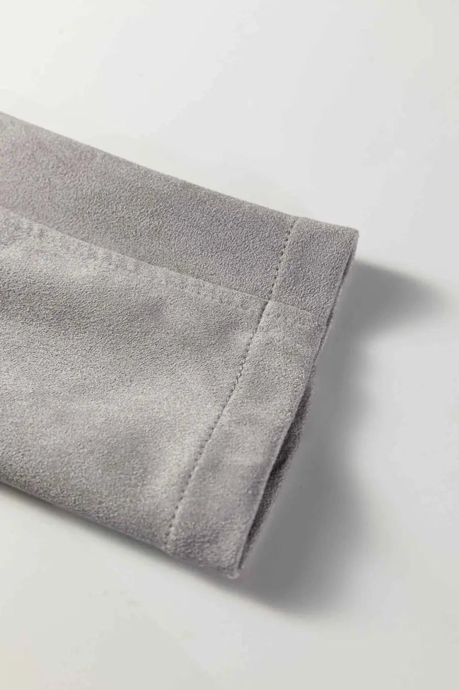 Detailed view of cuff on gray cropped fringe faux suede jacket, showcasing soft suede finish and precise stitching.