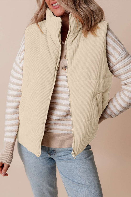 Ladies beige corduroy puffer gilet with stand neck and front zipper, styled with striped sweater and jeans for casual winter wear.