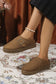 Brown vegan suede clog slippers with a buckle on a floral rug