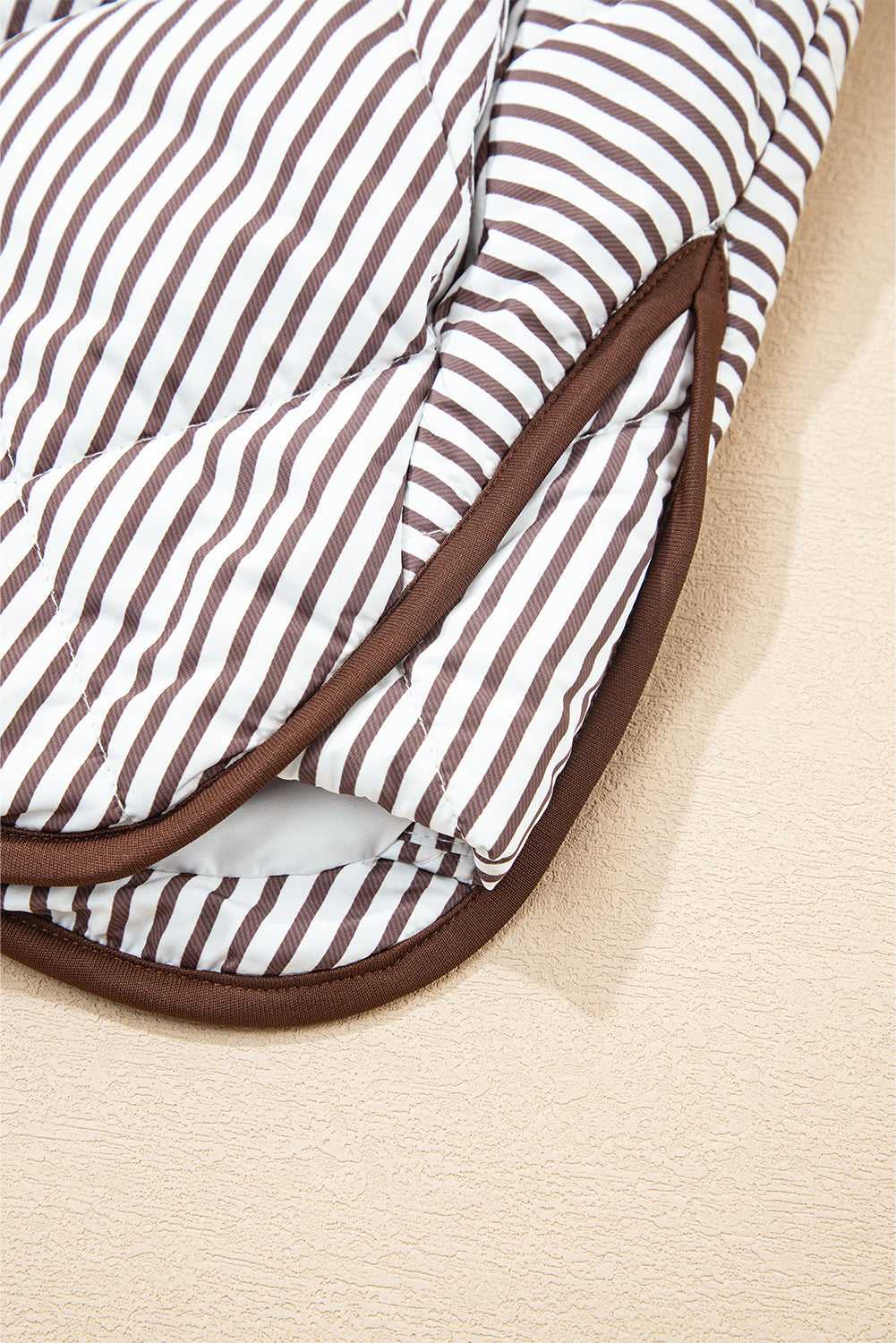 Hem detail of the Stripe Snap Winter Vest with curved edge and brown piping, enhancing its casual and comfortable fit.