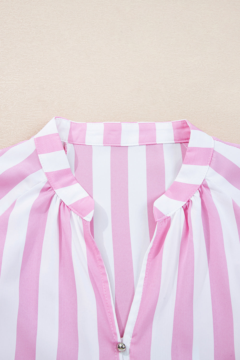 Close-up of a pink and white striped garment with a beige background