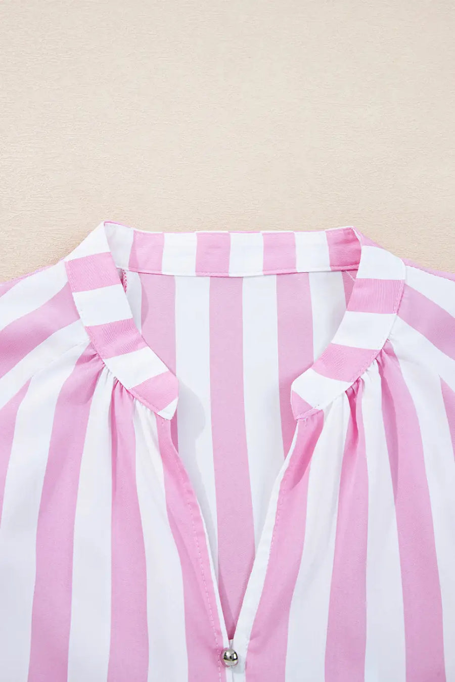 Close-up of a pink and white striped garment with a beige background