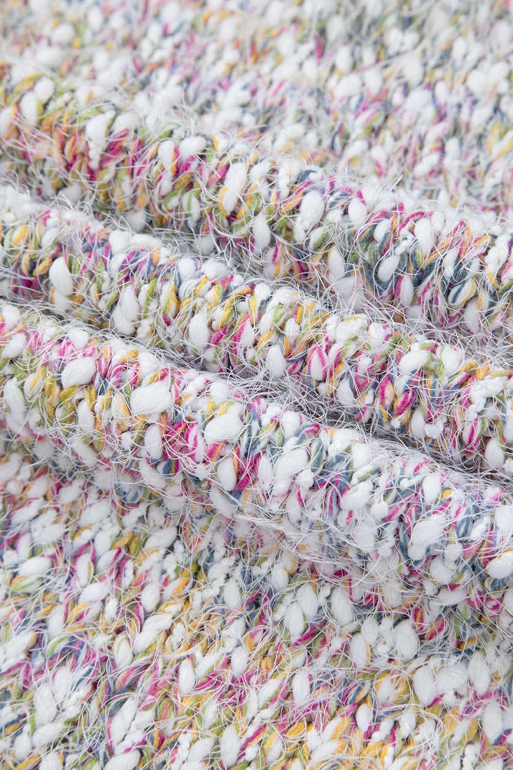 Close-up of confetti knit fabric in white with yellow, pink, and blue threads, highlighting texture and quality of the cardigan.