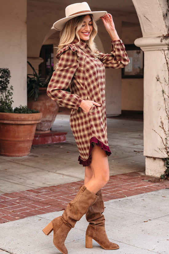 Woman wearing a plaid dress and brown boots in an outdoor setting.