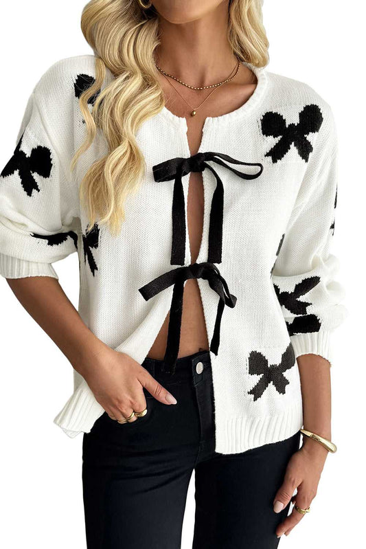 White Bow‑Lace Knit Cardigan styled with black pants, featuring black bow motifs and front ribbon ties for a chic and cozy women’s look.