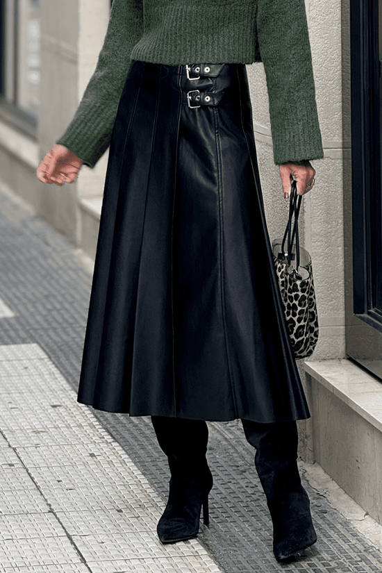 Black Faux Leather Pleated Flared Skirt | FashionFitz styled with green sweater and black boots, showcasing its edgy pleats and dual buckle waist.