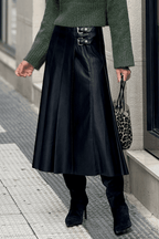 Black Faux Leather Pleated Flared Skirt | FashionFitz styled with green sweater and black boots, showcasing its edgy pleats and dual buckle waist.