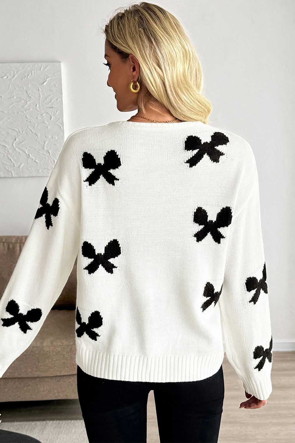 Back view of White Bow‑Lace Knit Cardigan showcasing black bow motifs on a soft knit fabric, ideal for chic women’s knitwear styling.