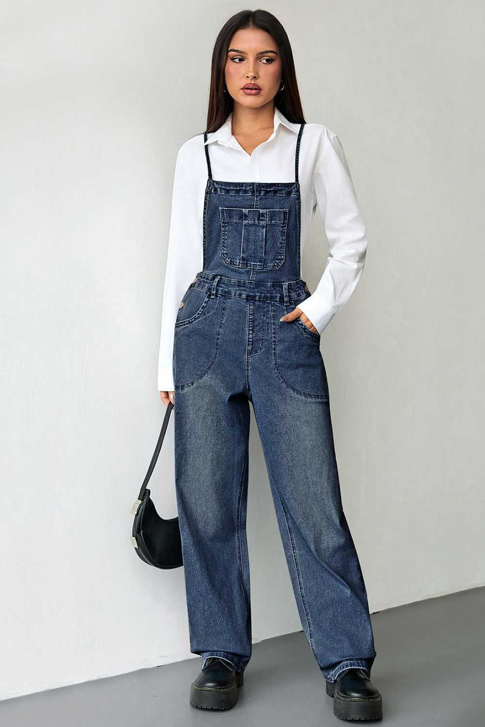 Versatile dark blue baggy denim overalls for women with a solid color design and medium elasticity. Styled with black platform shoes.