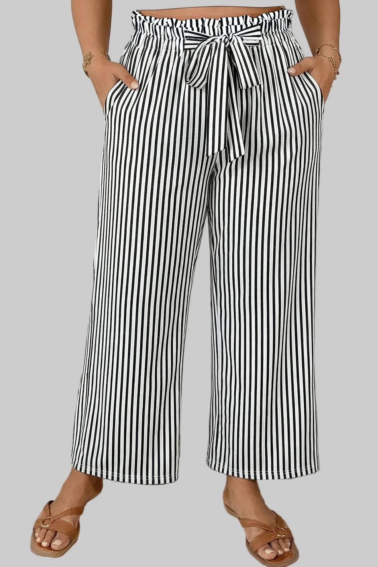 Person wearing black and white striped wide-leg pants in a bathroom setting.