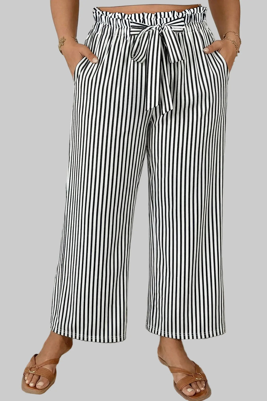 Person wearing black and white striped wide-leg pants in a bathroom setting.