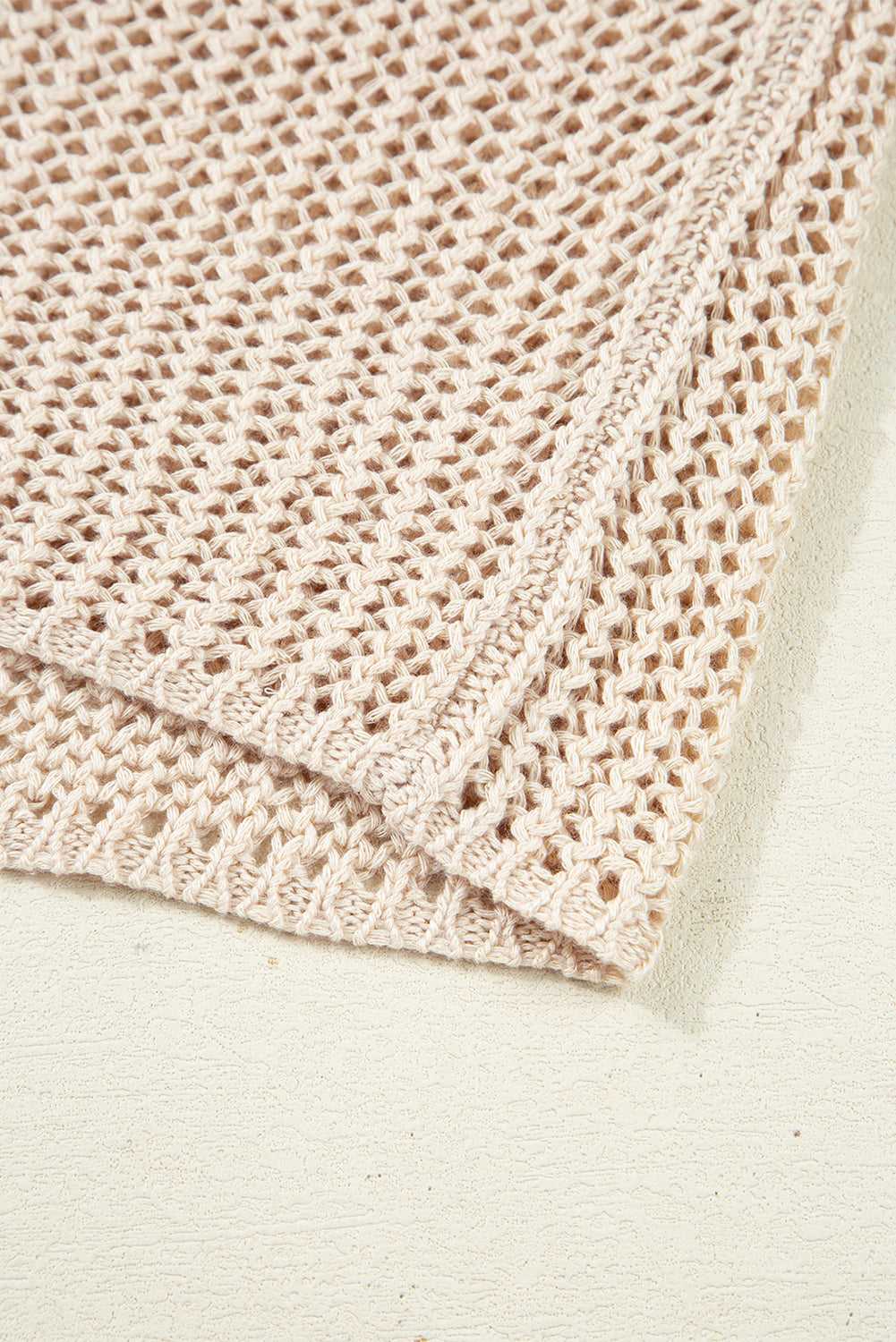 Close-up of a folded beige crochet blanket on a light background